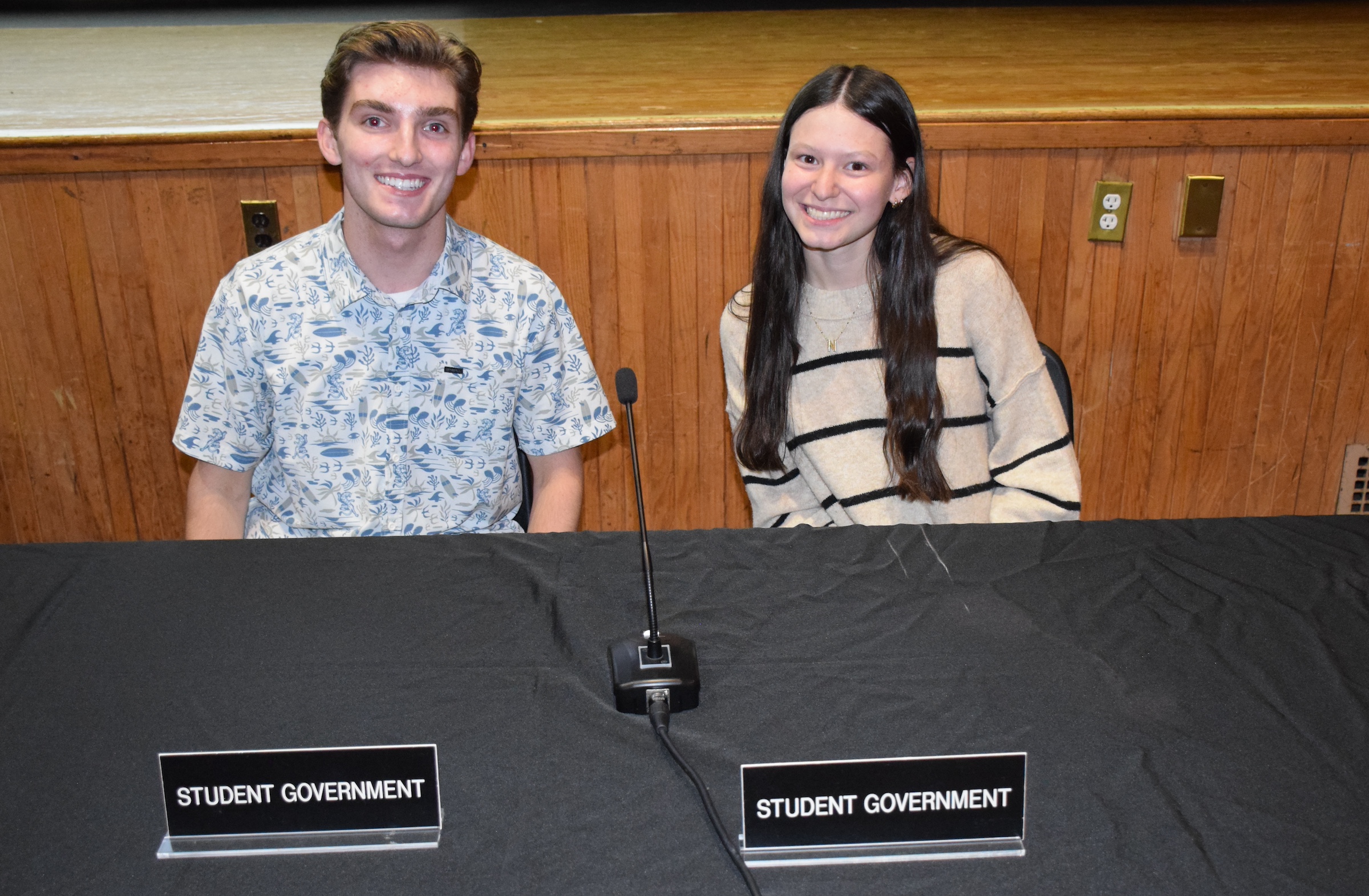 two students sitting at a table smiling